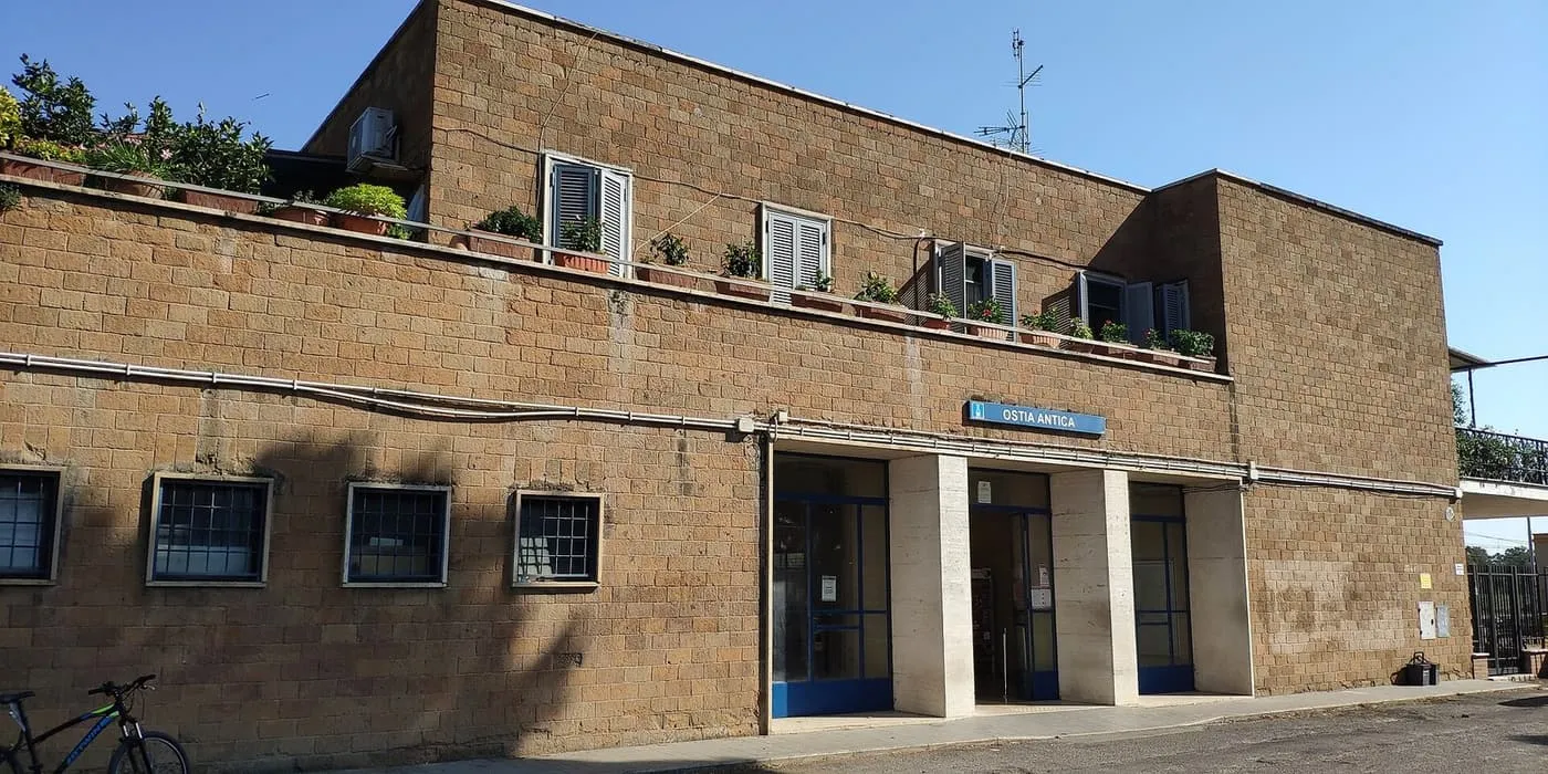 The brown stone-block front of Ostia Antica station, with its blue name sign above the entrance