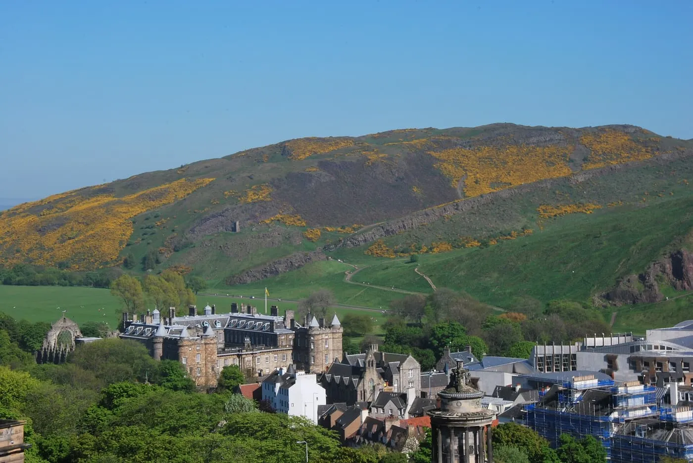 The Palace of Holyroodhouse beside the abbey ruins, with the gorse-covered slopes of Arthur's Seat rising behind