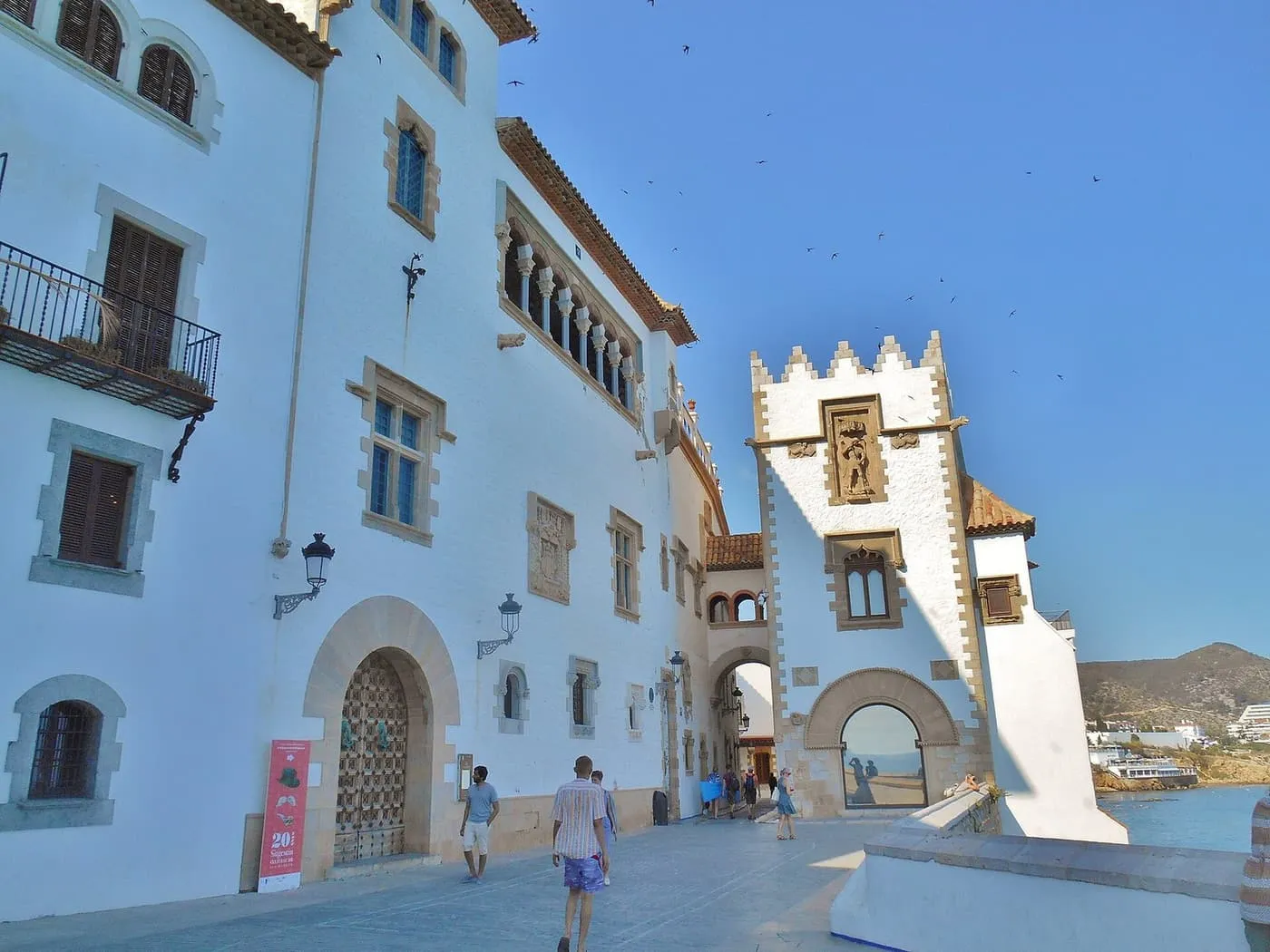 The whitewashed walls of the Palau Maricel in Sitges, with a crenellated tower and an arch opening on to the sea