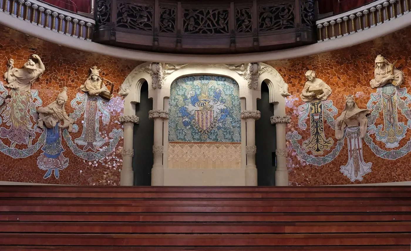 The curved wall behind the stage, with sculpted and mosaic muses either side of the Catalan coat of arms