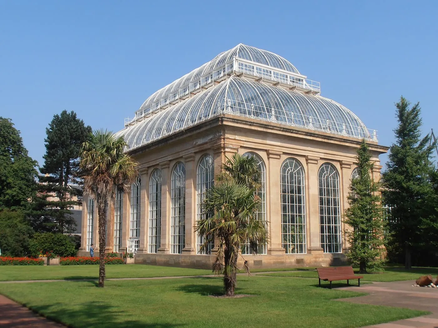 The glass-domed Palm House with tall arched windows, seen across the lawn with palms in front