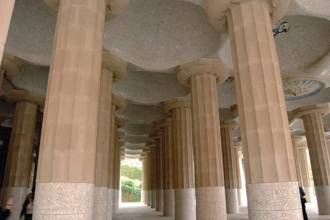 Rows of thick fluted stone columns holding up a white mosaic ceiling set with round tiled medallions