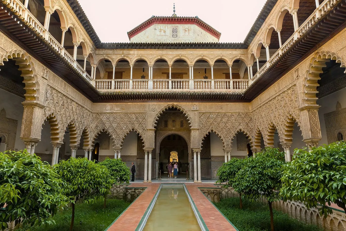 The Patio de las Doncellas, a long courtyard with a central pool, orange trees and carved arcades on two floors