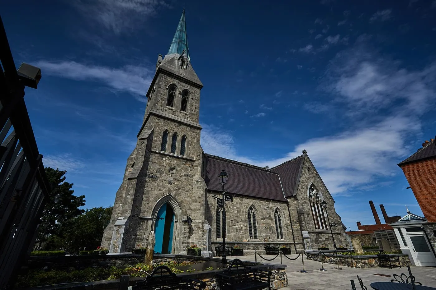 The grey stone tower and spire of the restored St James's Church that houses the Pearse Lyons Distillery, with a turquoise door at its foot