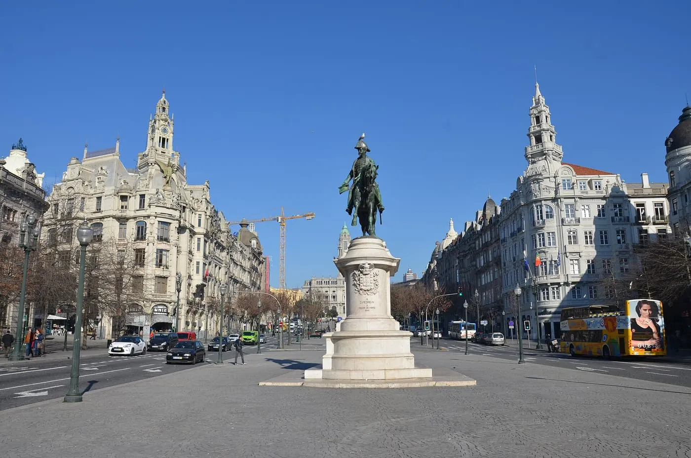 The bronze equestrian statue of King Pedro IV on its white plinth in Praça da Liberdade, with the ornate buildings of the avenue on either side under a blue sky