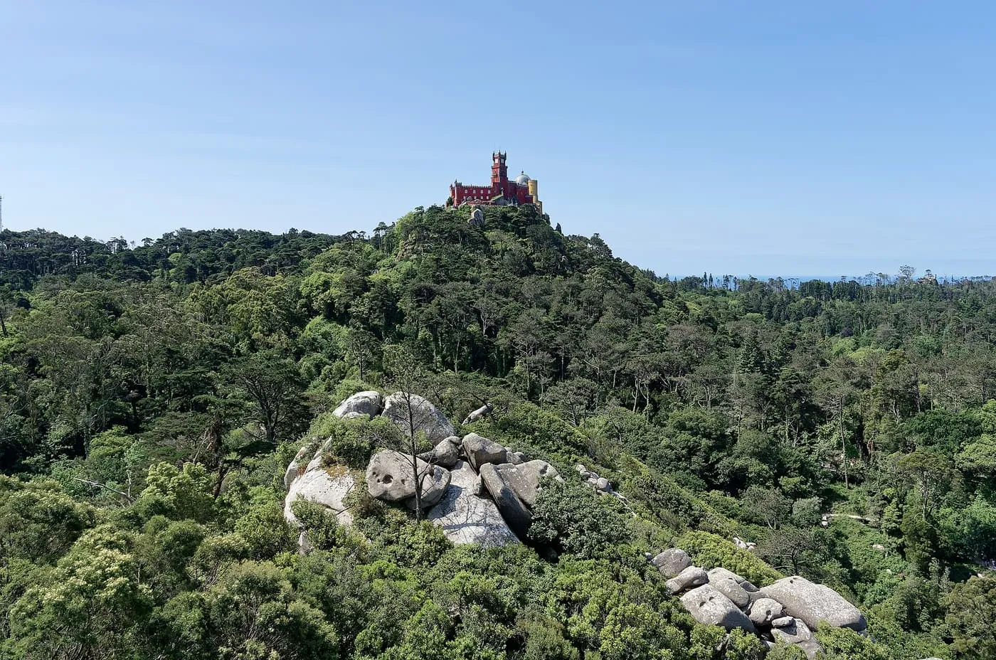 Pena Palace on its wooded hilltop, seen across a valley of pines and granite boulders