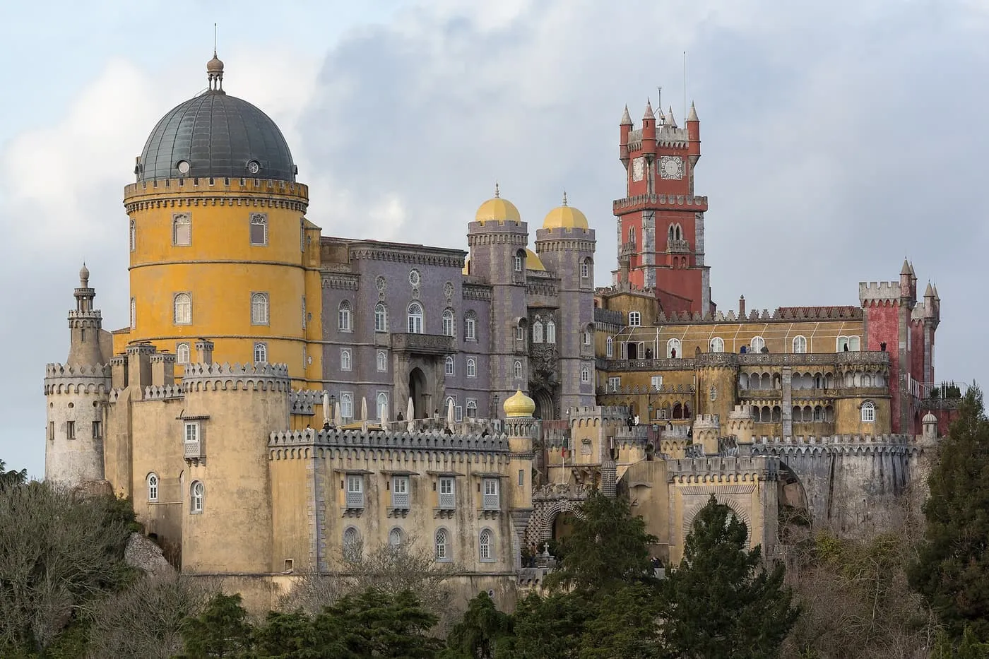 Pena Palace's yellow rotunda, violet-tiled wall and red clock tower rising above the park walls