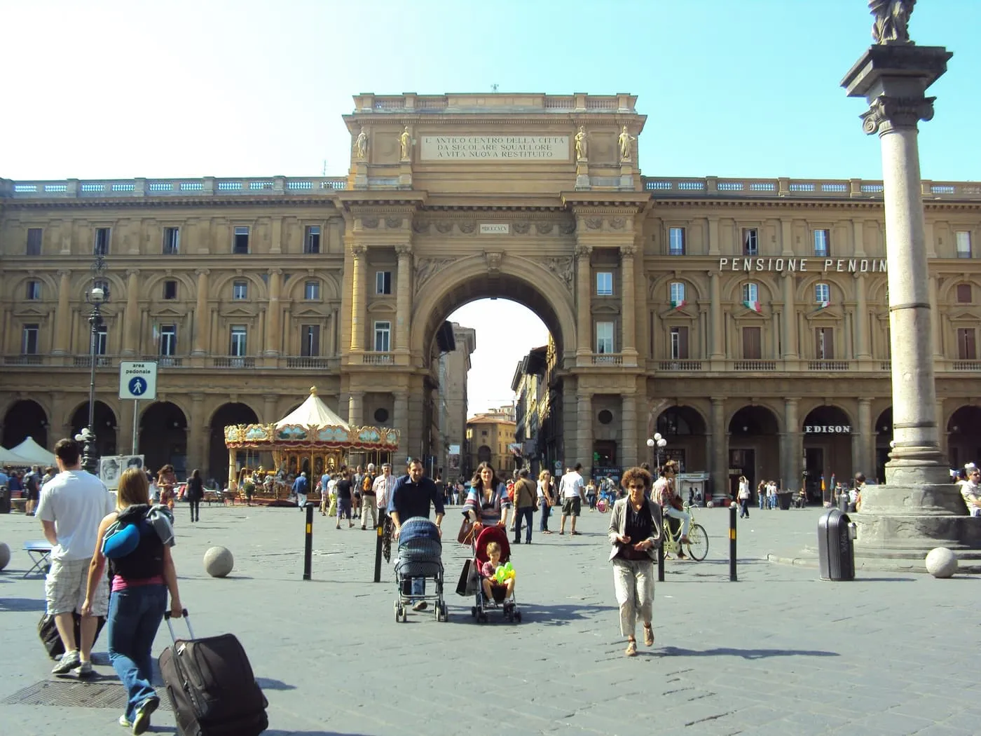 The triumphal arch and the column in the middle of Piazza della Repubblica, with a carousel in front of the arch