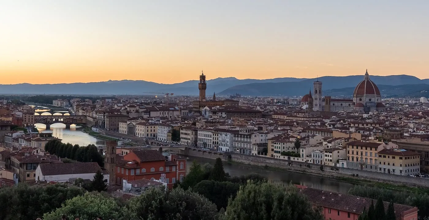 Florence at sunset from Piazzale Michelangelo, with the Arno, the Ponte Vecchio, the Palazzo Vecchio tower and the Duomo dome under an orange sky