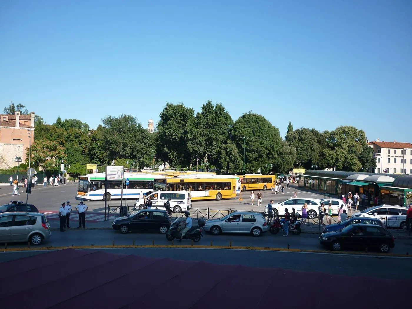 Buses and taxis at the Piazzale Roma terminal, with trees behind and travellers waiting