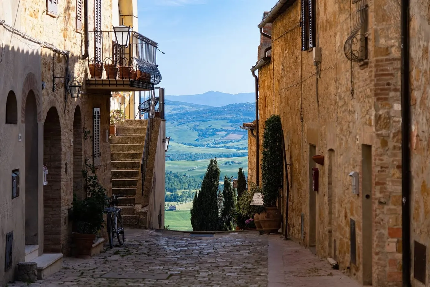 A stone street in Pienza ending in a view over the green hills of the Val d'Orcia