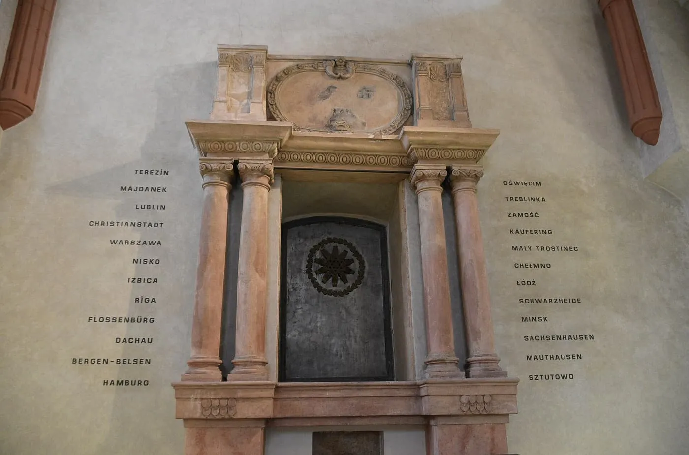 The Torah ark niche in the Pinkas Synagogue, framed by the names of concentration camps written on the wall