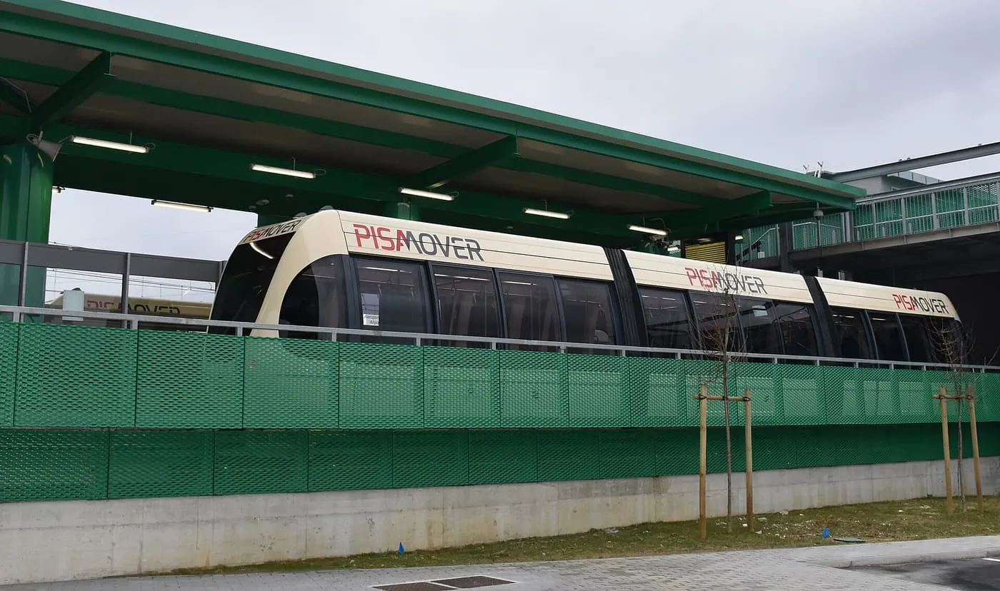 A PisaMover car at a station platform under a green canopy