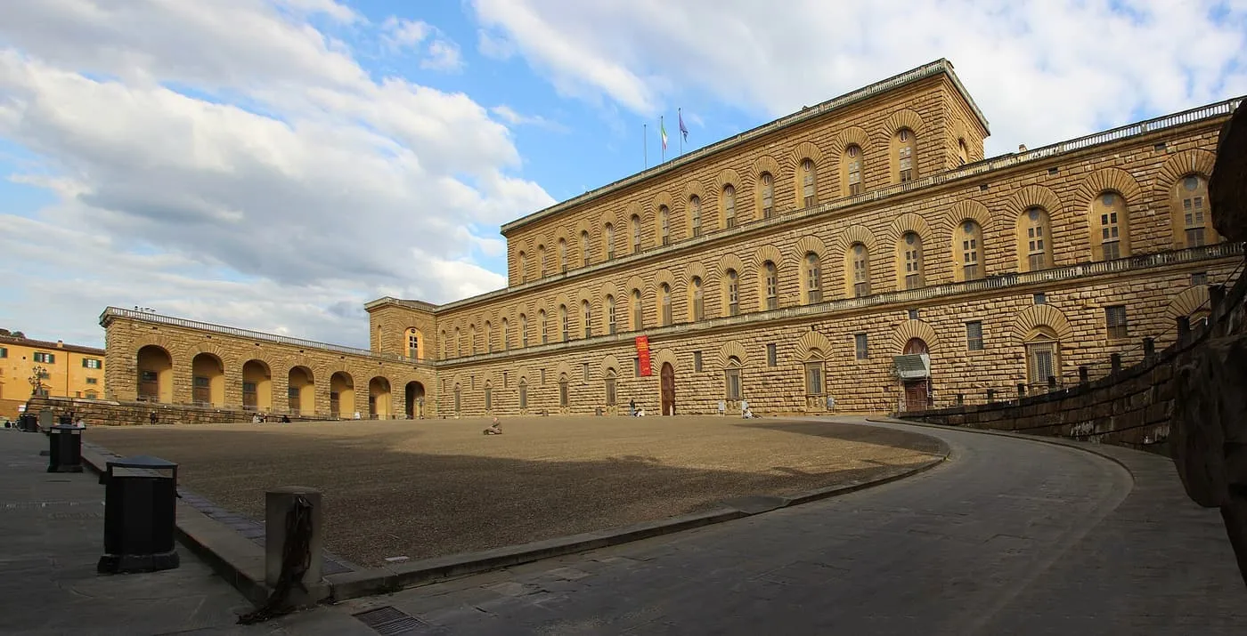 The long rusticated stone front of Palazzo Pitti curving round its sloping piazza