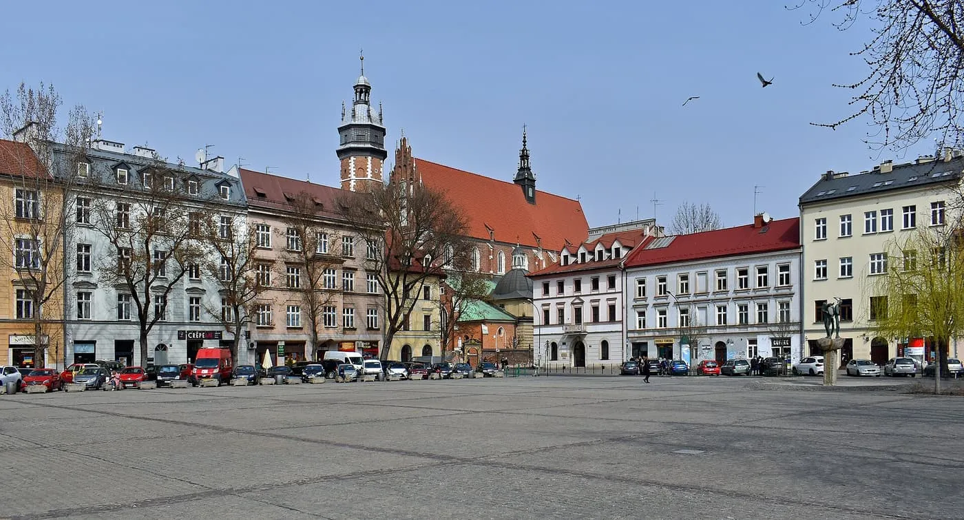 Plac Wolnica in Kazimierz, a wide paved square with townhouses and a red-roofed church behind them