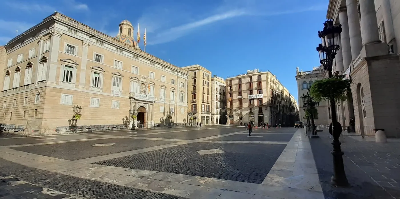 Plaça de Sant Jaume, a wide empty paved square with the stone Palau de la Generalitat on the left and tall townhouses along the far side
