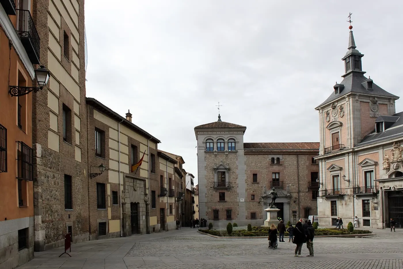 The Plaza de la Villa in Madrid, with the brick and stone Casa de la Villa at right, a stone tower house across the square and a statue in a small garden