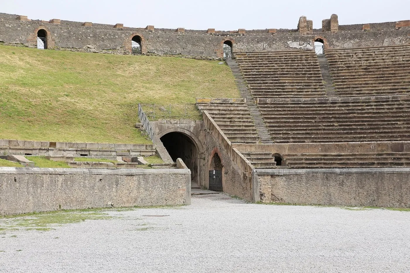 The arena and stepped seating of the amphitheatre at Pompeii, with a grass bank on the left