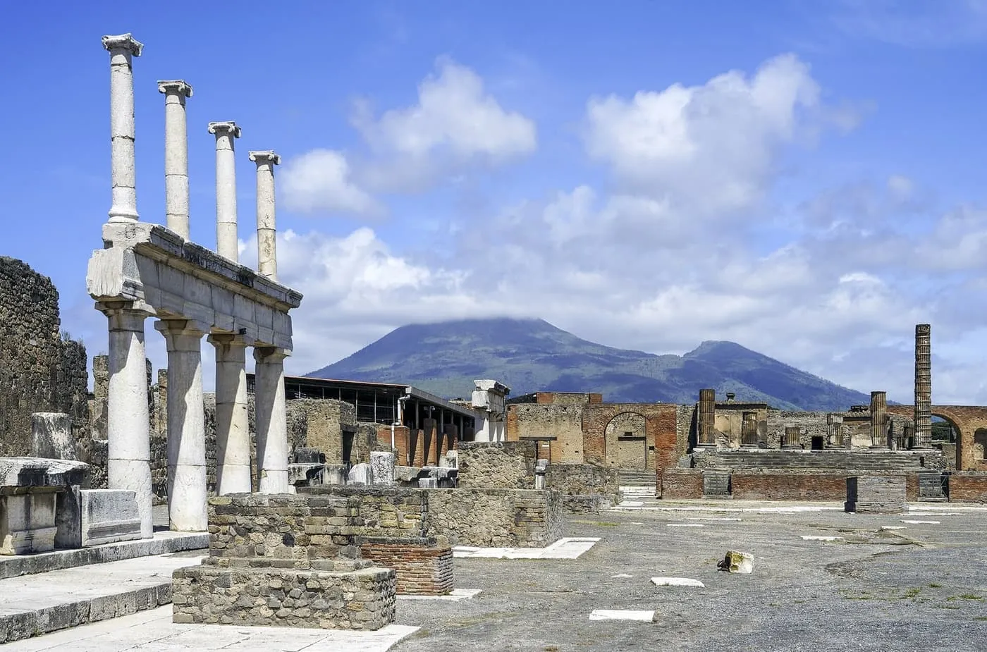 Columns and ruined buildings in the Forum at Pompeii, with Vesuvius behind