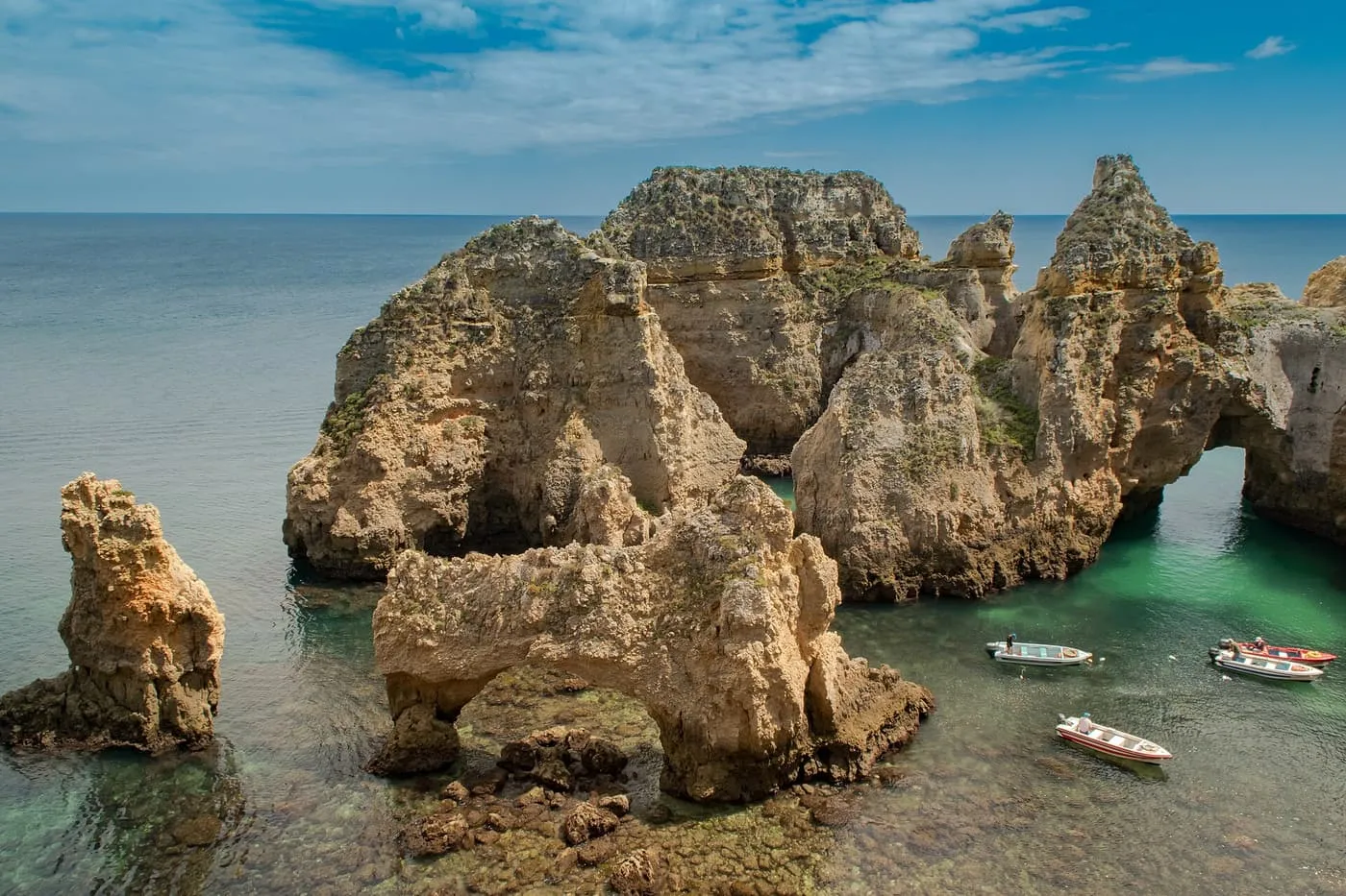Sandstone sea stacks and arches at Ponta da Piedade near Lagos, with small boats in the green water
