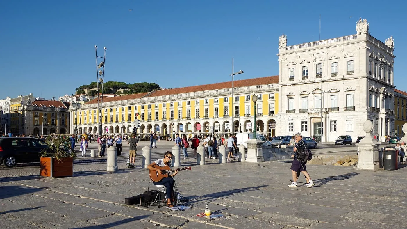 Praça do Comércio, with its yellow arcades and a street musician in the foreground