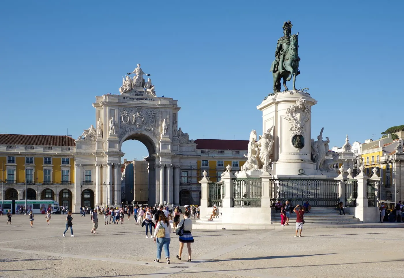 The Praça do Comércio under a blue sky, with the Rua Augusta Arch and the equestrian statue of King José I, and the yellow arcaded buildings round the square
