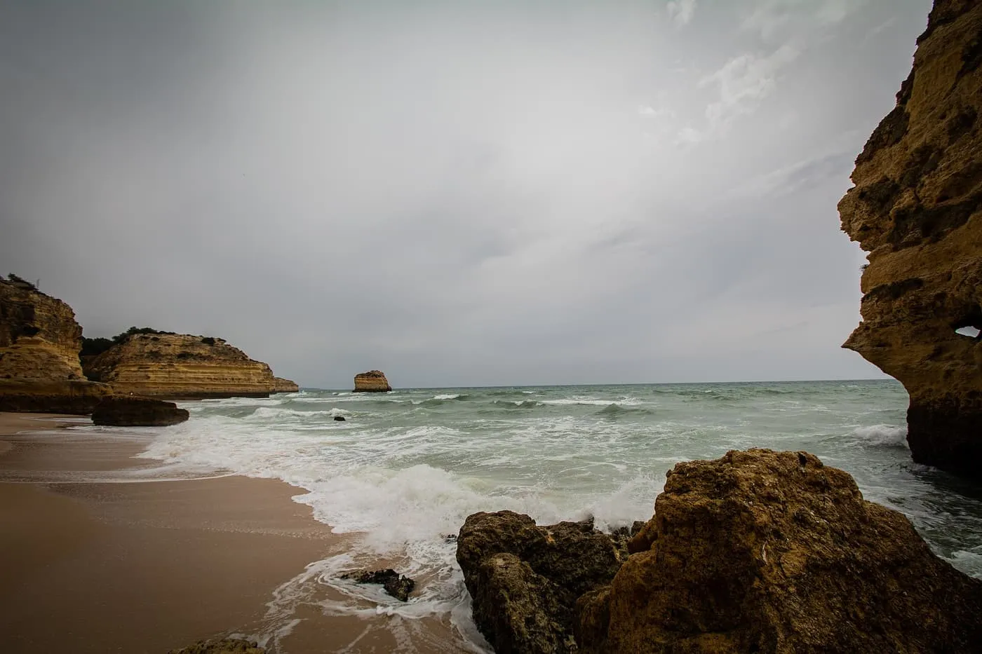 Golden cliffs around a small cove beach on the Lagoa coast, seen from the sea