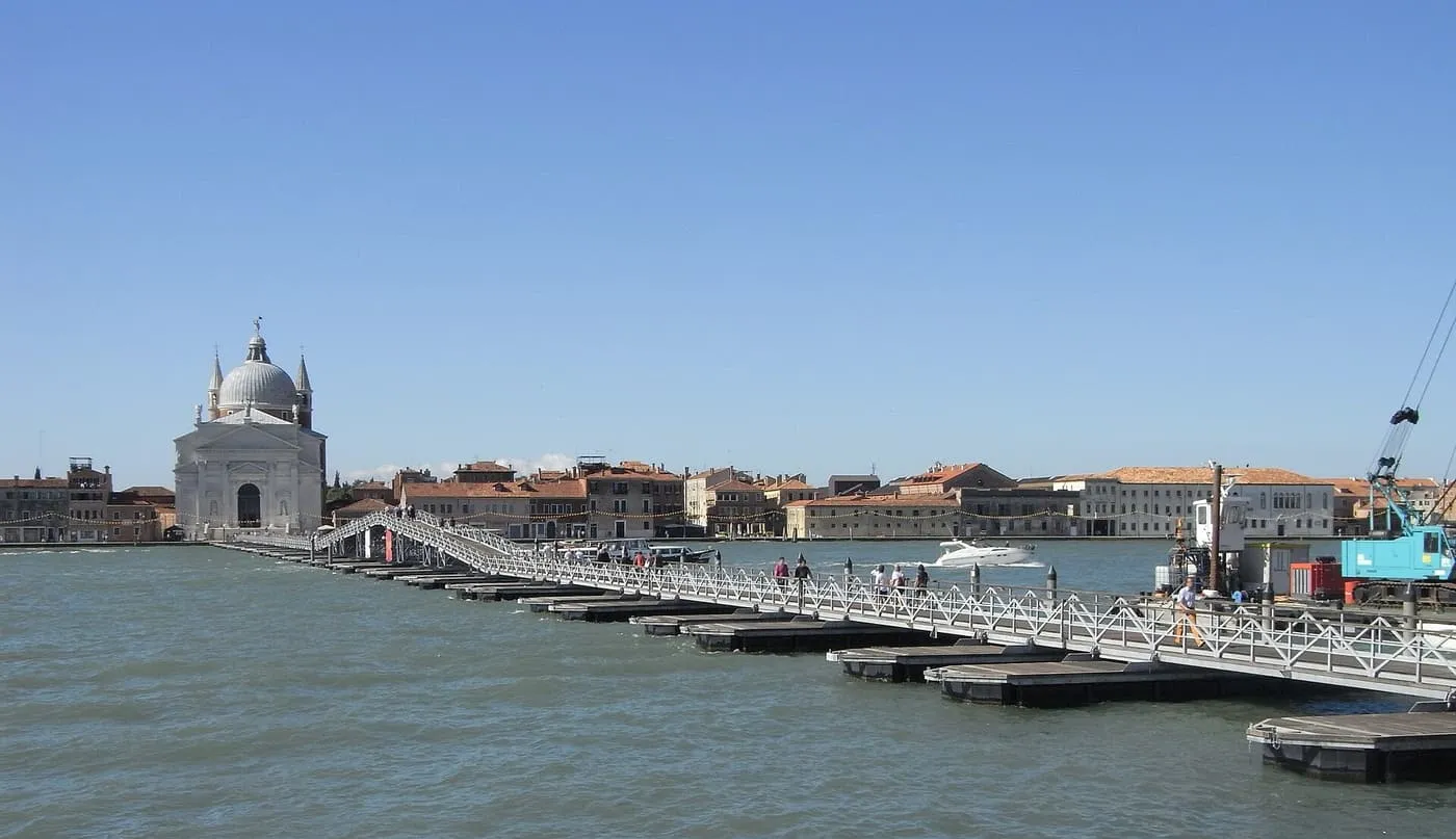 A white pontoon bridge stretching across the water towards the domed church of the Redentore