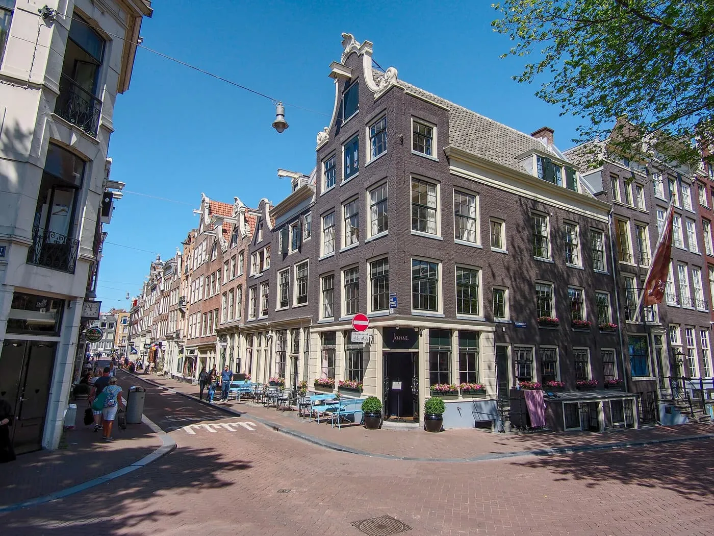 A corner of the Reestraat at the Keizersgracht, with a dark brick corner house with a scrolled gable and a street of narrow gabled houses running away to the left