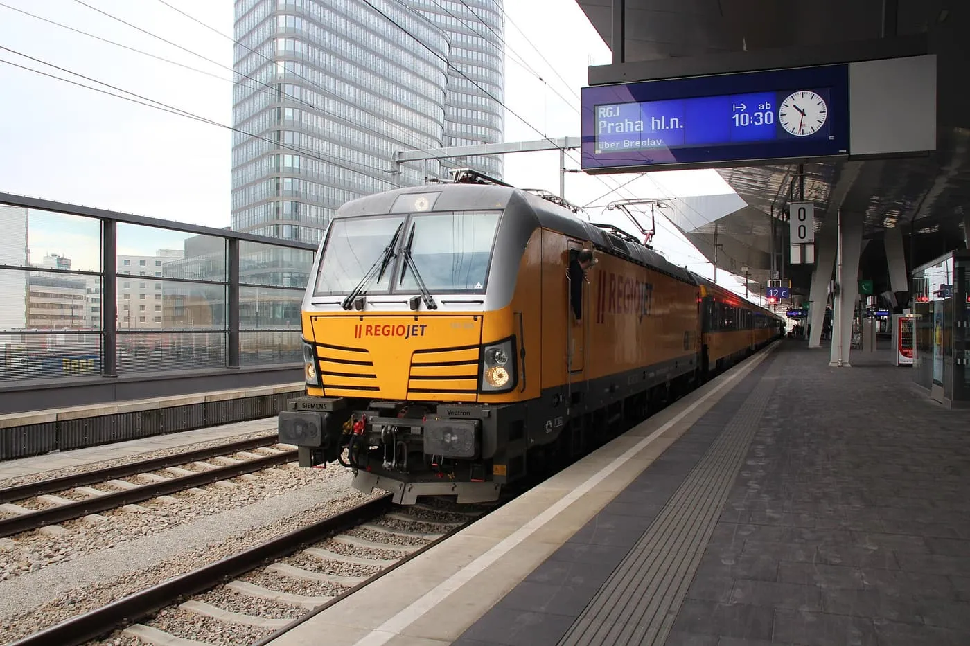 A yellow RegioJet locomotive and train standing at a platform of Wien Hauptbahnhof