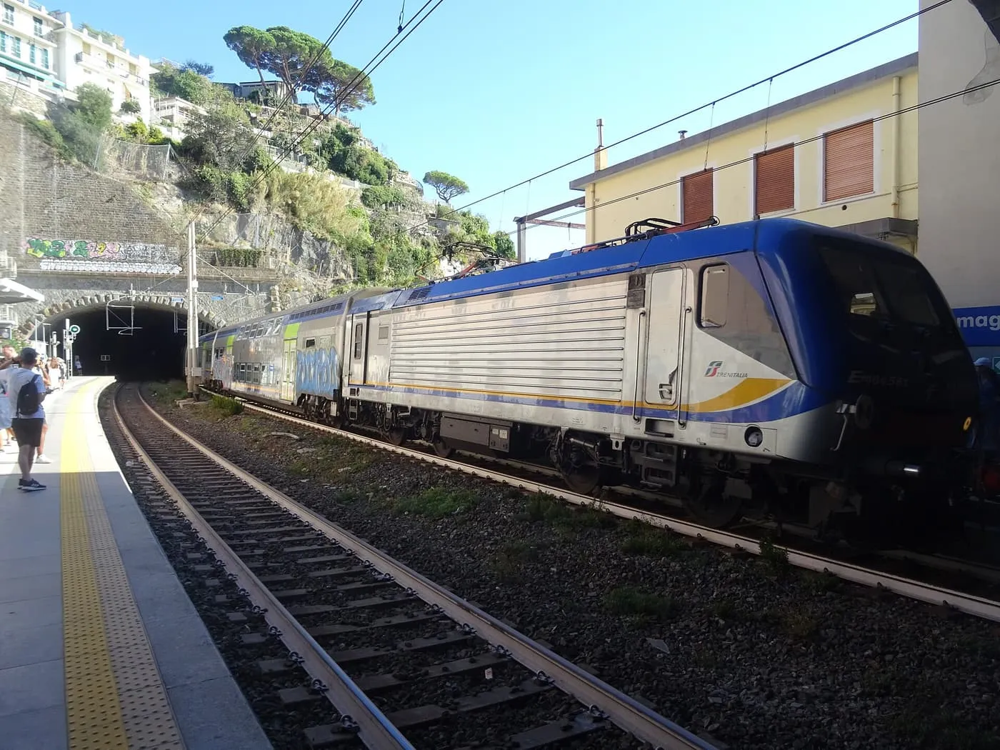 A Trenitalia regional train arriving at a platform at Riomaggiore, beside a tunnel mouth