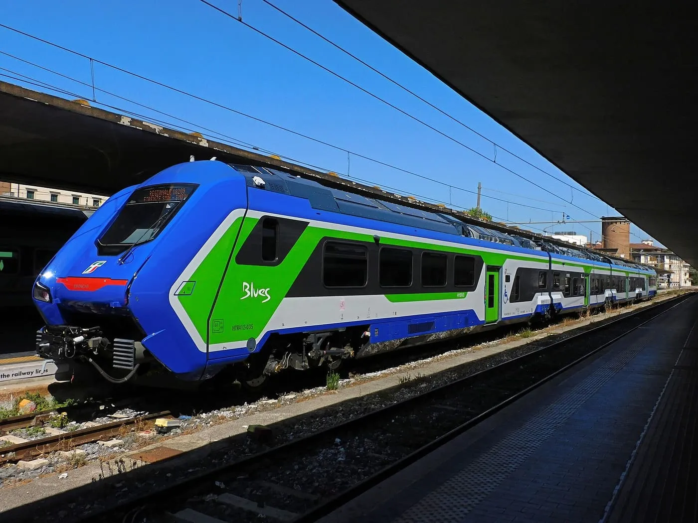 A blue and green Trenitalia regional train standing at a platform of Firenze Santa Maria Novella