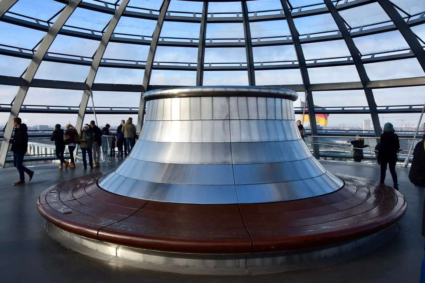 The mirrored cone at the centre of the Reichstag dome, with the glass of the dome around it and visitors on the walkway