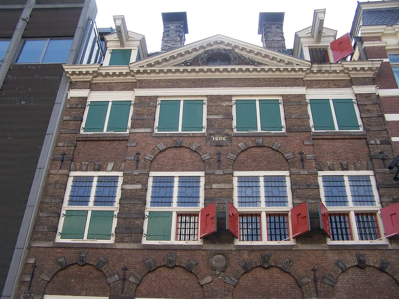 The brick front of the Rembrandt House, with a pediment, green and red shutters and the date 1606 on the wall