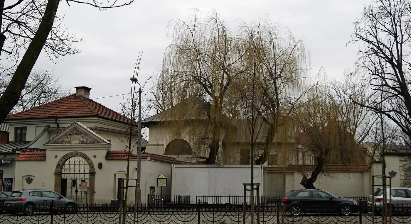 The street wall and gate of the Remuh Synagogue on ul. Szeroka, with parked cars in front
