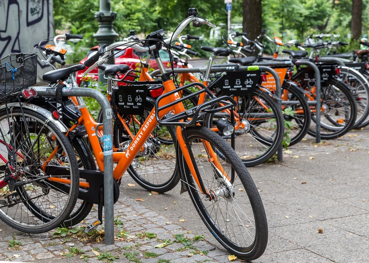 Orange rental bicycles locked to racks on a cobbled pavement in Kreuzberg