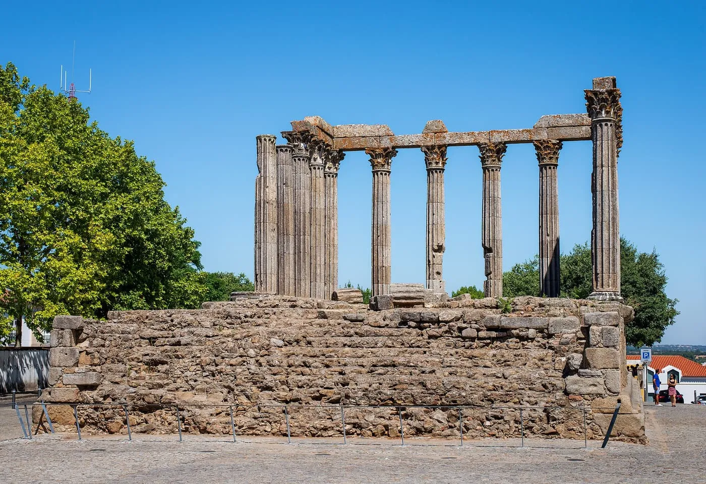 The Corinthian columns of Évora's Roman temple above its granite base, under a clear blue sky