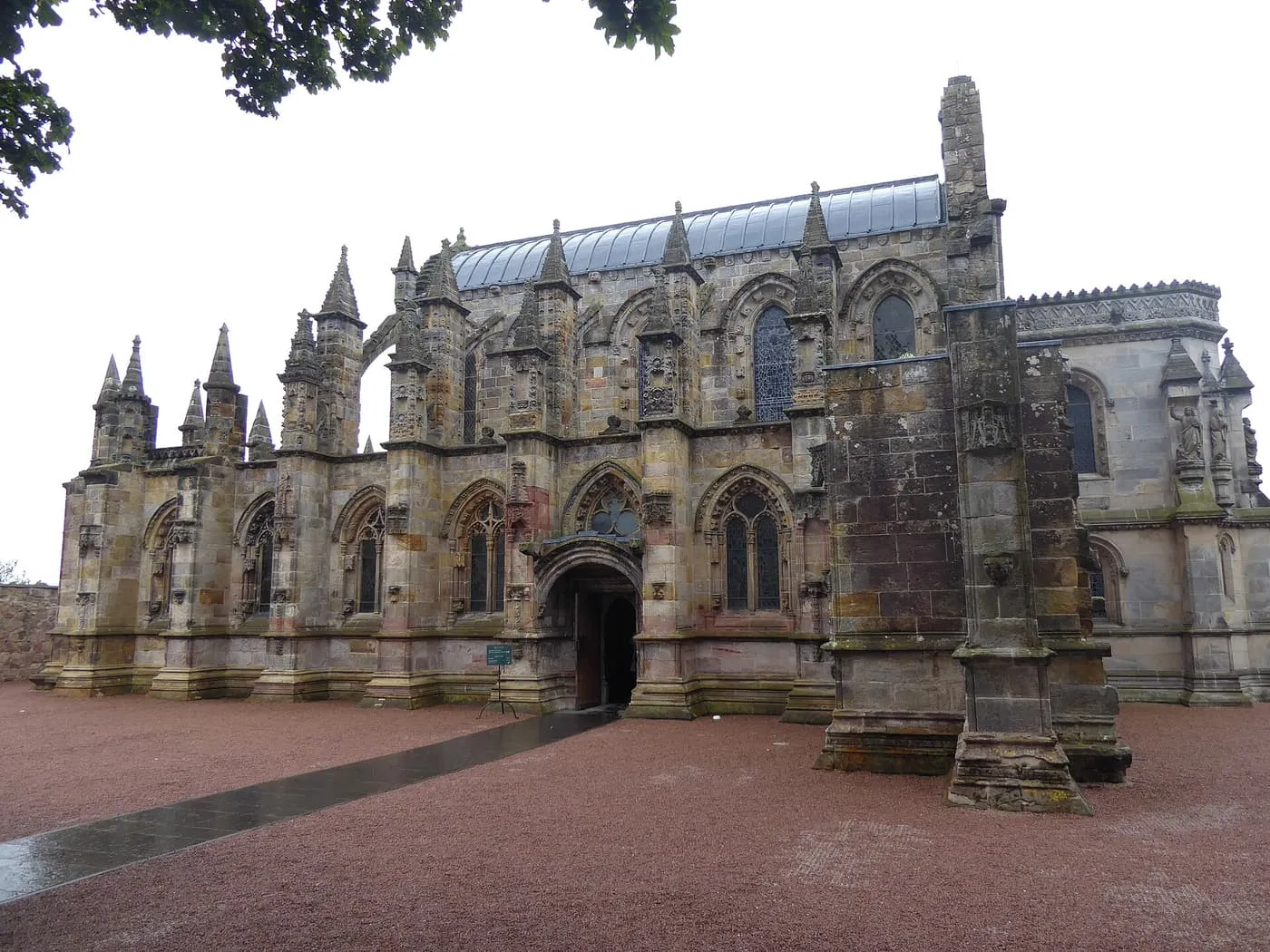 Rosslyn Chapel from the gravel forecourt, with pinnacles along the roofline and a buttress in the foreground