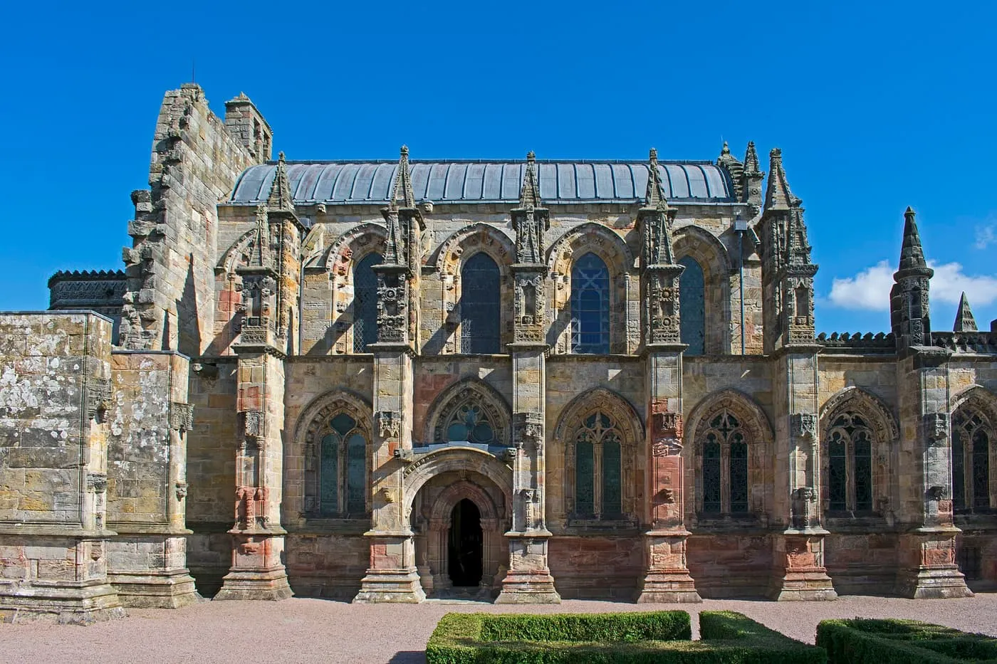 The carved south front of Rosslyn Chapel, with pinnacled buttresses, a small doorway and a slate roof
