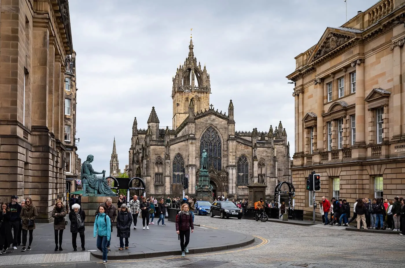 St Giles' Cathedral and its crown spire at the head of a cobbled junction on the Royal Mile, with pedestrians crossing in the foreground