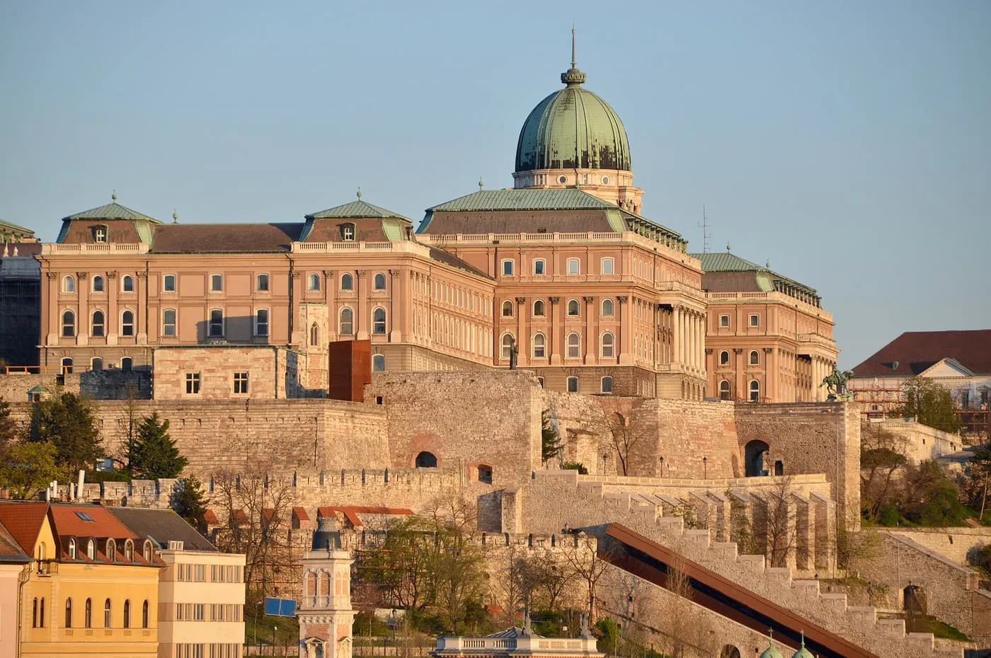 The Royal Palace on Buda Castle Hill, its green dome and pink-walled wings rising above the castle walls in low sun