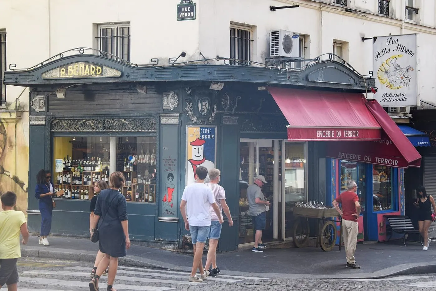 A delicatessen and pâtisserie on the corner of Rue Lepic and Rue Véron in Montmartre, with wine bottles in the window and a red awning