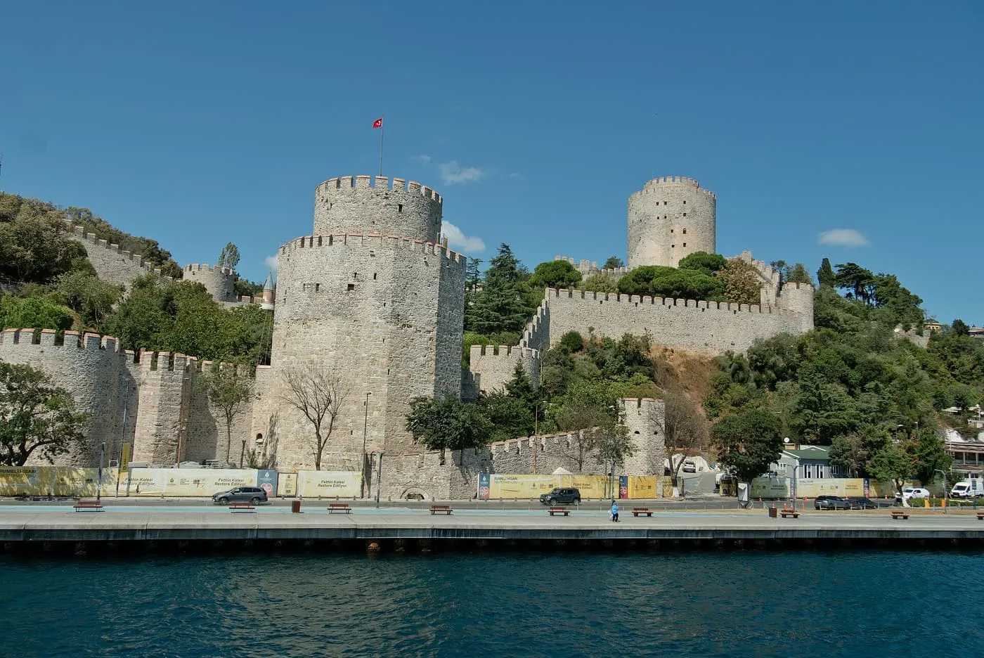 The stone towers and crenellated walls of Rumeli Fortress on the shore above the Bosphorus, under a blue sky
