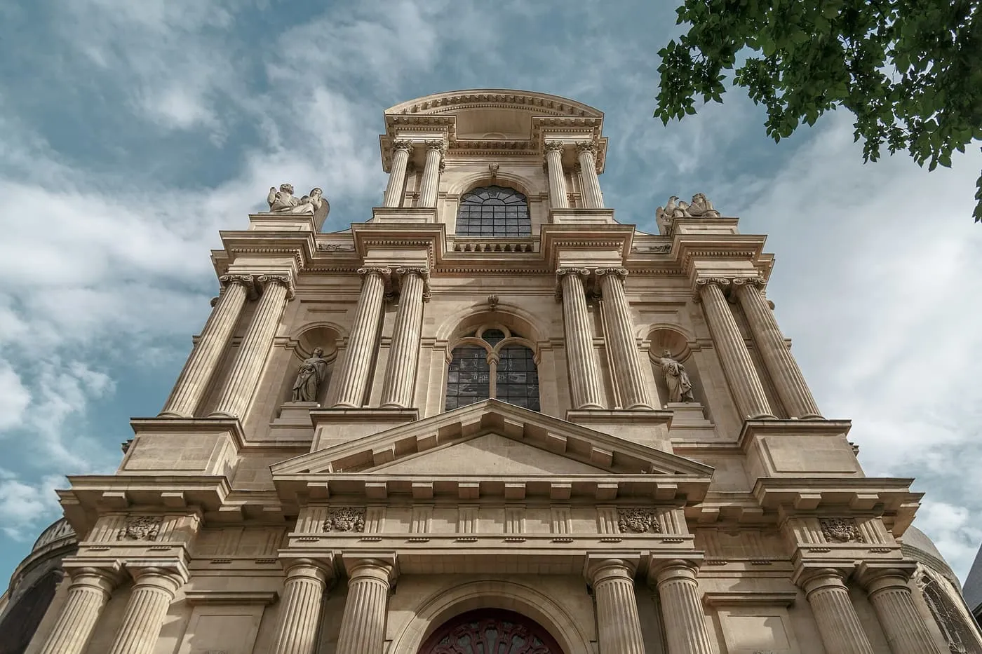 The classical front of Saint-Gervais, with paired columns on three storeys rising to a curved pediment against a cloudy sky
