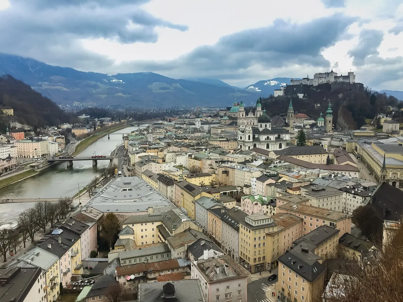Salzburg's old town beside the Salzach, with Hohensalzburg Fortress on the hill above and mountains beyond
