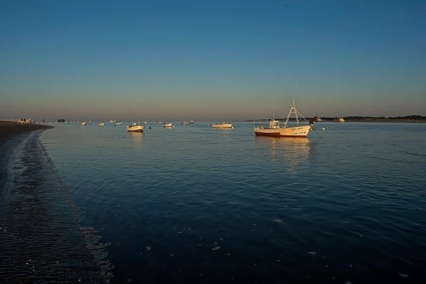 Fishing boats at anchor on the Guadalquivir estuary at Bajo de Guía in Sanlúcar de Barrameda, in low evening light