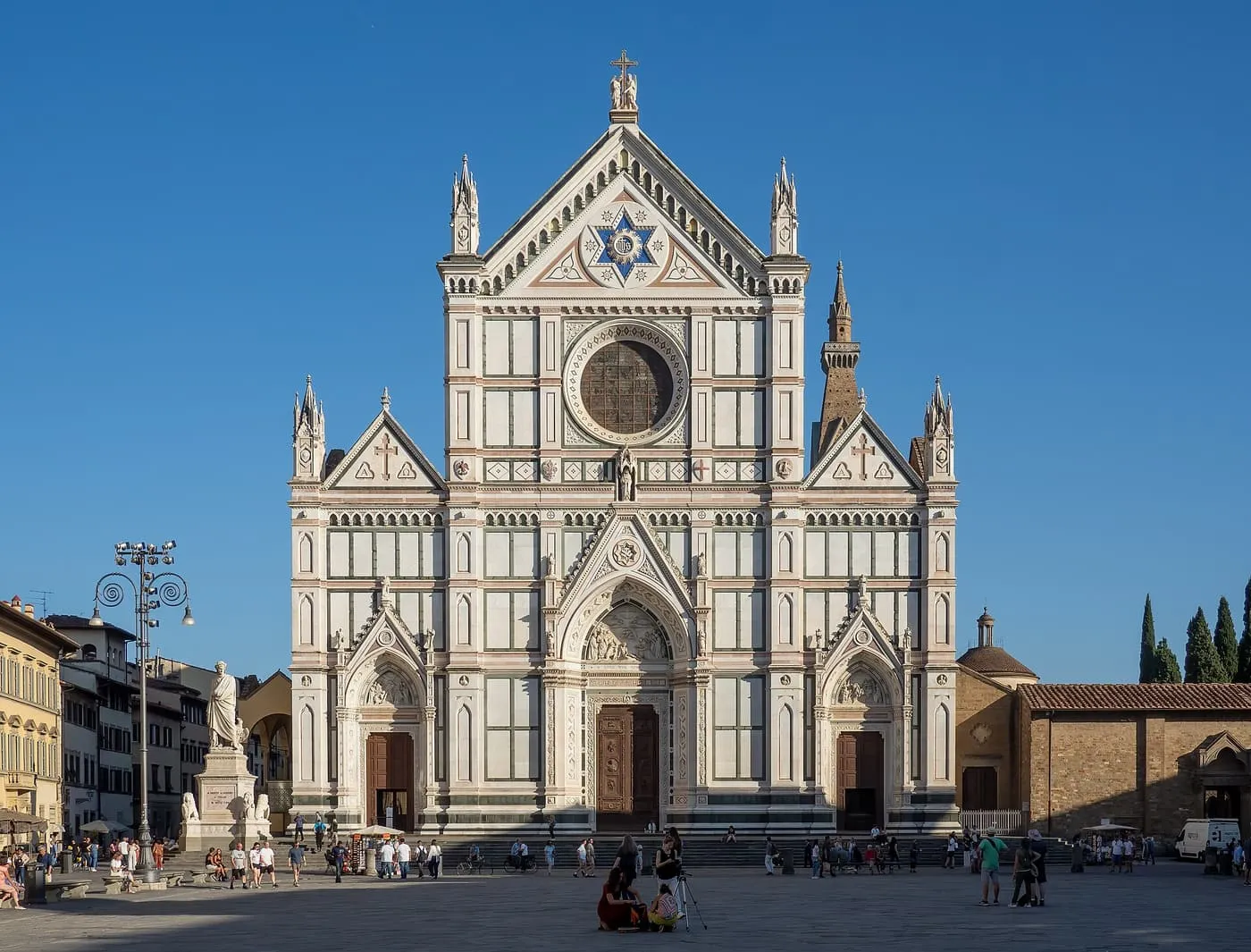 The white, green and pink marble front of Santa Croce, with the statue of Dante at the left of the steps