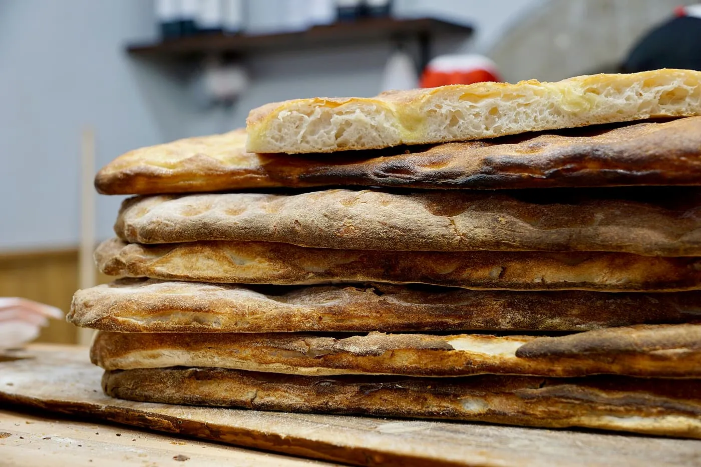 A stack of flat golden sheets of schiacciata on a baker's board