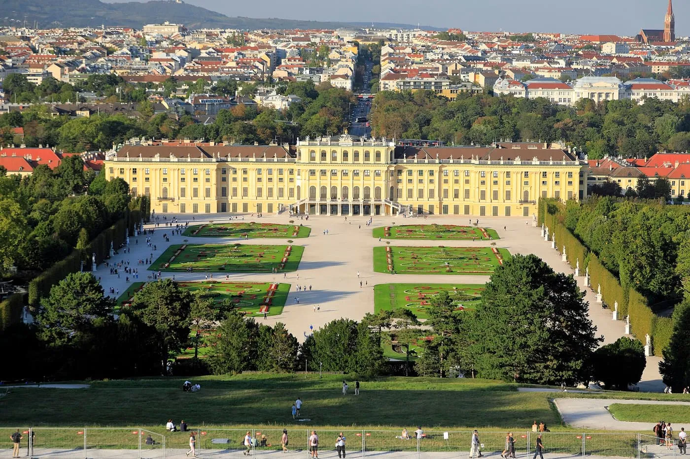 Schönbrunn Palace and its formal parterres seen from the roof of the Gloriette, with the city and a tree-lined avenue beyond