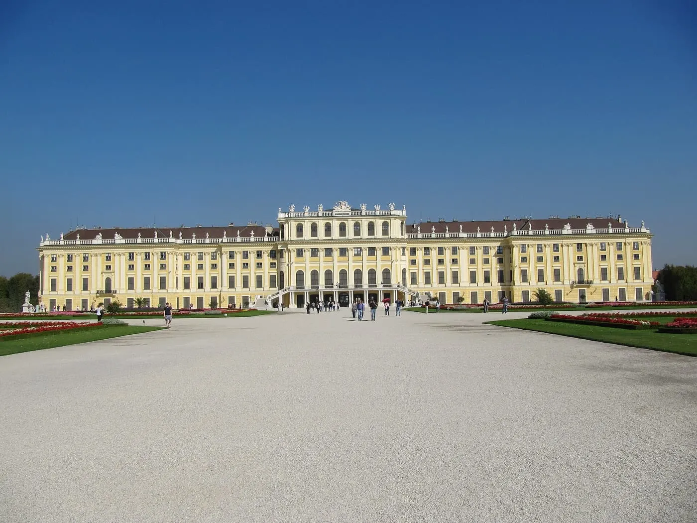 The long yellow garden front of Schönbrunn Palace across an empty gravel parterre under a clear sky